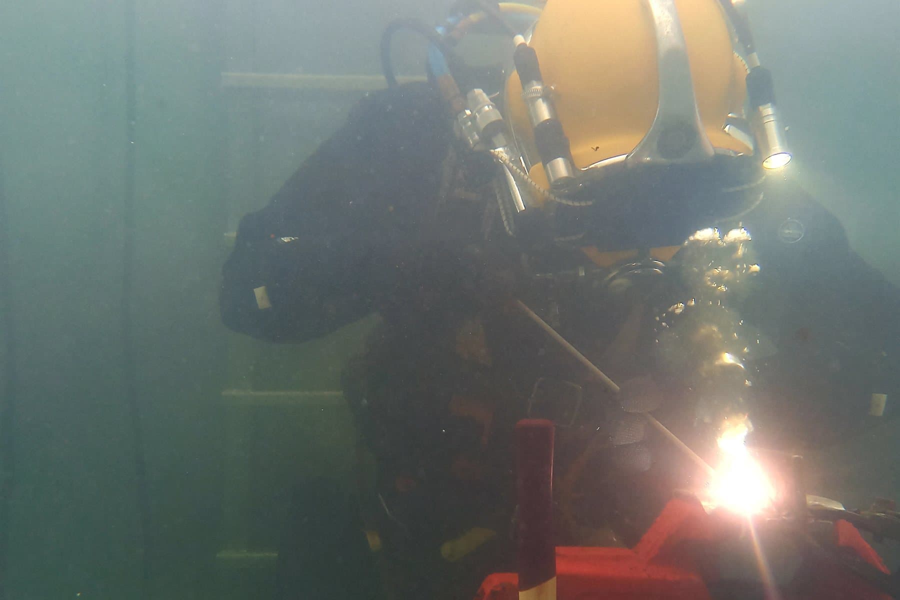 Taucher beim Unterwasserschweißen im Schweißtank, mit deutlich sichtbarem Lichtbogen