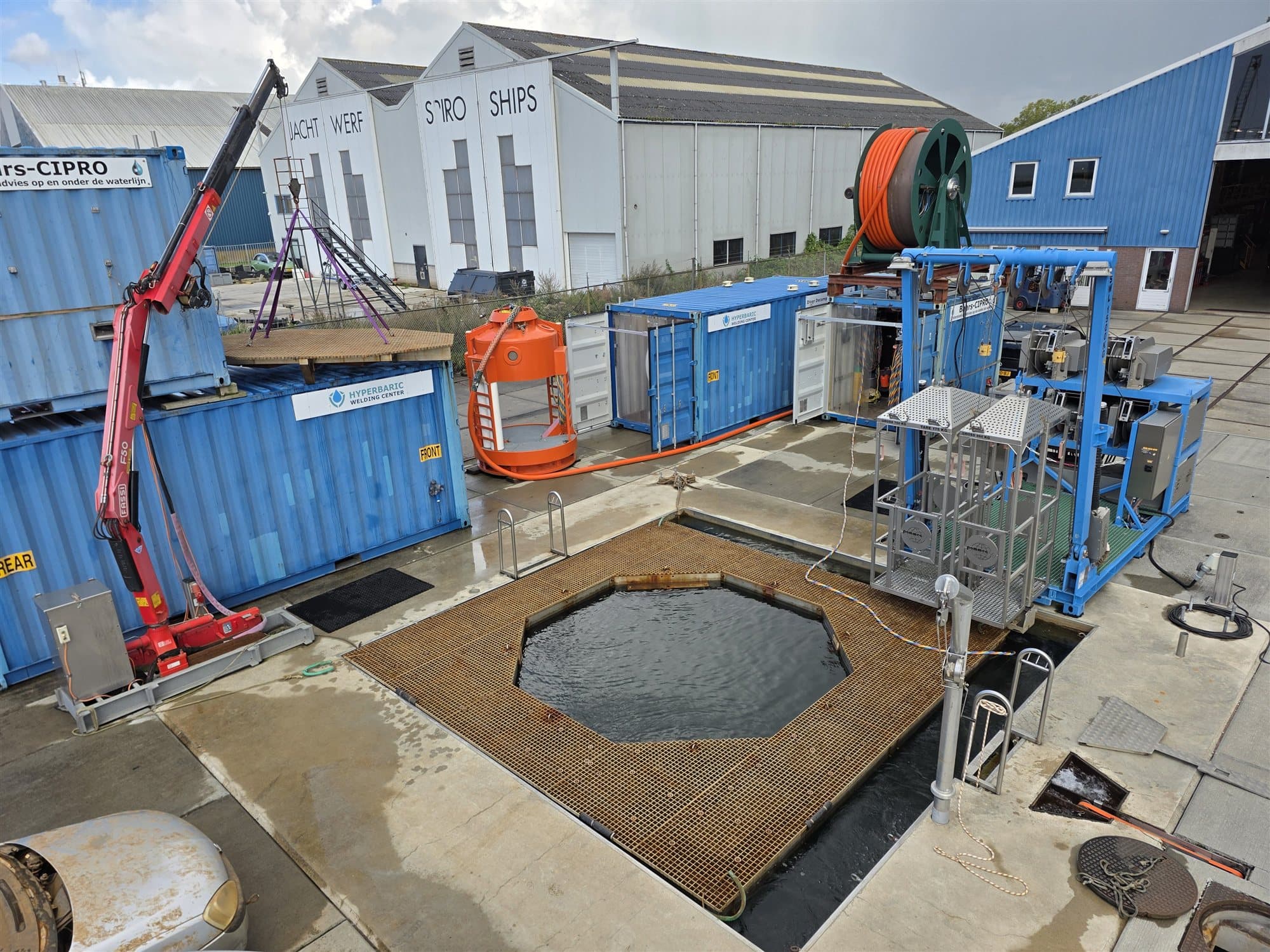 Übersicht über das 21 Meter tiefe Tauchbecken und das Außengelände, mit Deko-Containern und dem LARS.