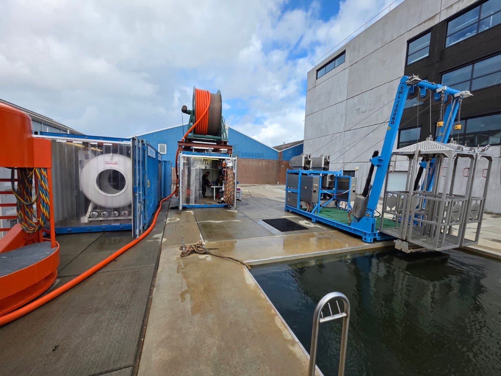 Weite Ansicht des Außengeländes des Hyperbaric Welding Center: Deko-Container, Schlauchhaspel und der LARS mit Tauchkorb über dem Tauchbecken.